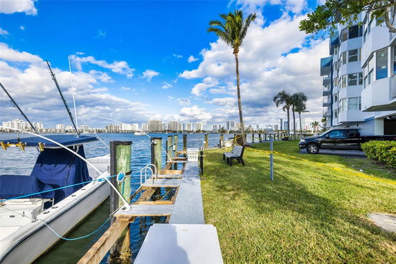 Building adjacent to a water body with moored boats and a view of distant cityscape.