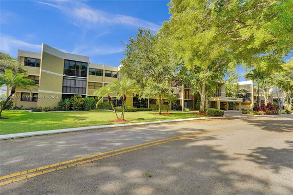 Front view of a multi-story building with large windows and surrounded by trees.