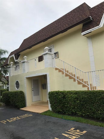 Front view of a two-story building with a staircase and brown shingled roof.