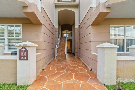 Front view of a multi-story building entrance with stairs and a sign showing unit numbers.