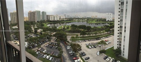 Panoramic view of high-rise buildings and a pond with surrounding green areas.