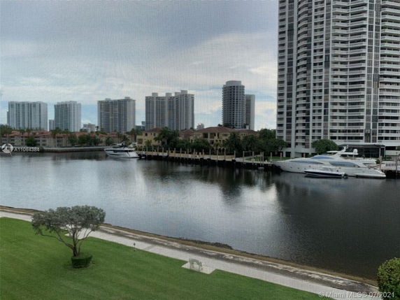 View of high-rise buildings near a waterfront with yachts docked along the edge.