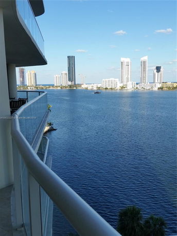 View from a balcony overlooking water and distant high-rise buildings.