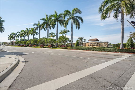 Entrance view of The Isles at Bayshore with palm trees and road in the foreground.