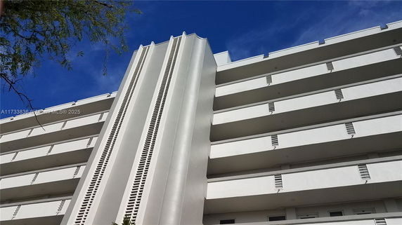Front view of a multi-story building with white facade and balconies.