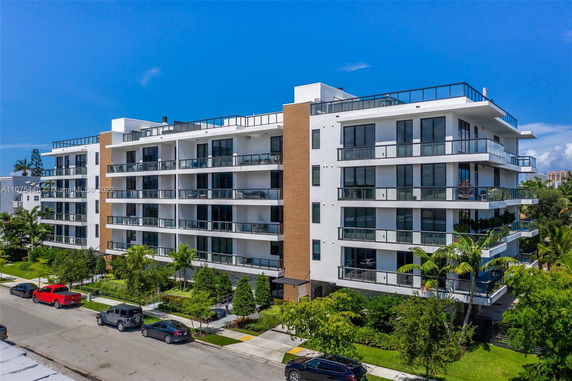 Front view of a multi-story apartment building with balconies and glass railings.