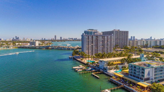 Panoramic view of waterfront buildings and bridge over a waterway.