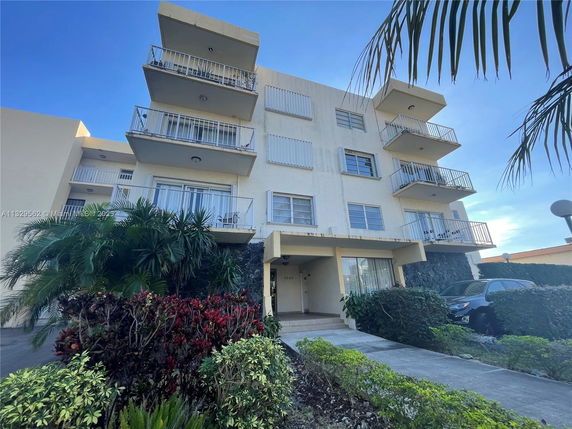 Front view of a multi-story building with balconies and a walkway leading to the entrance.