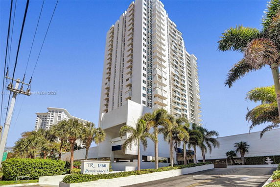 Front view of a tall residential building with multiple balconies.