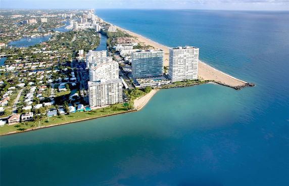 Aerial panoramic view of coastal cityscape with high-rise buildings and beach.