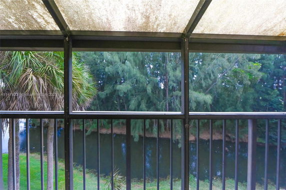 View through a screened balcony showcasing trees and a water body.