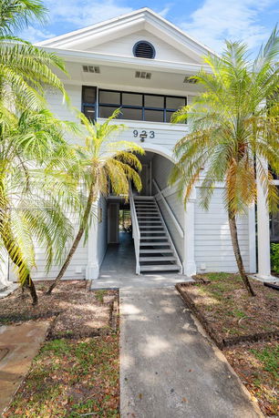Front view of a two-story building with an exterior staircase and white siding.