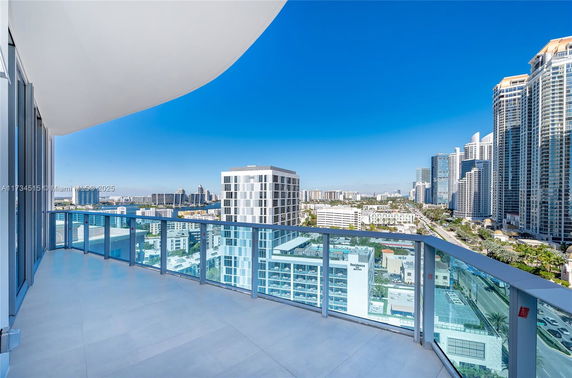 Panoramic view from a high-rise building balcony overlooking a cityscape with skyscrapers and blue sky.