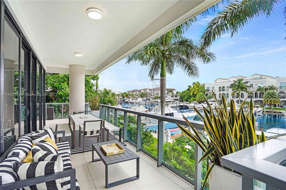 View from a balcony overlooking a marina with boats and palm trees.