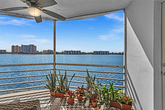 View from an outdoor balcony overlooking a body of water with distant buildings.