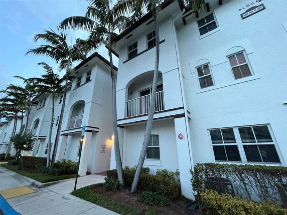 Front view of a multi-story residential building with balconies and white facade.