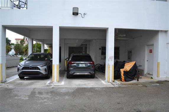 Covered parking space with two vehicles and bicycles.