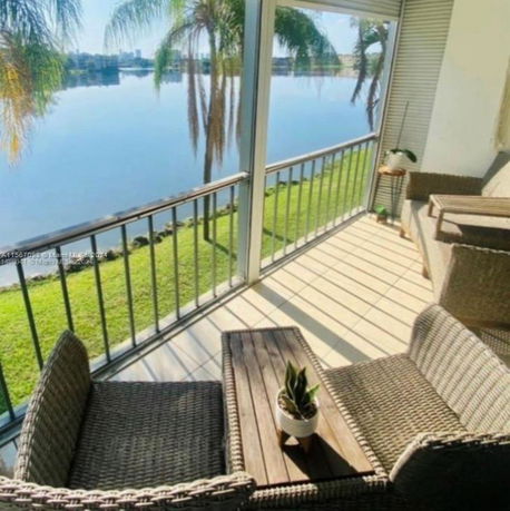 View from a balcony overlooking a scenic lake and palm trees.