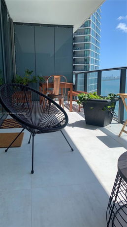 Balcony view with outdoor seating and a view of surrounding buildings and water.