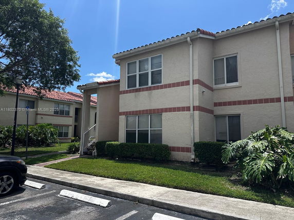 Front view of a two-story residential building with a red-tiled roof and light-colored walls.
