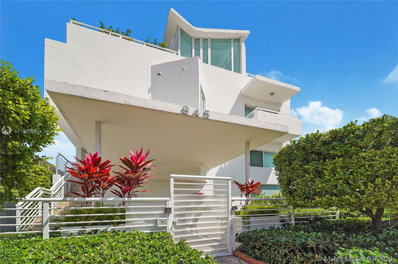 Front view of a modern multi-story house with angular design and large windows.