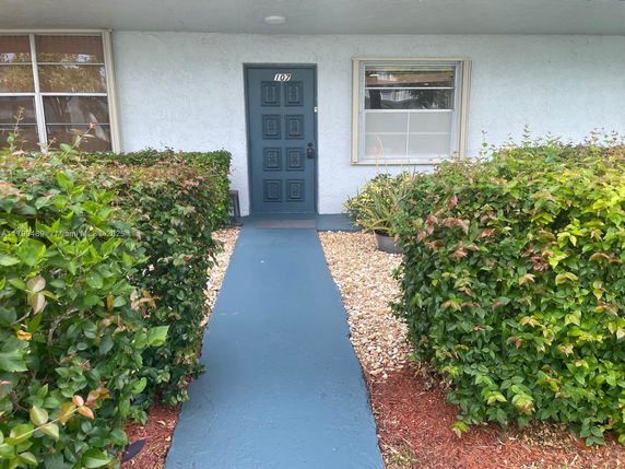 Front view of a house with a blue door and surrounding shrubbery.