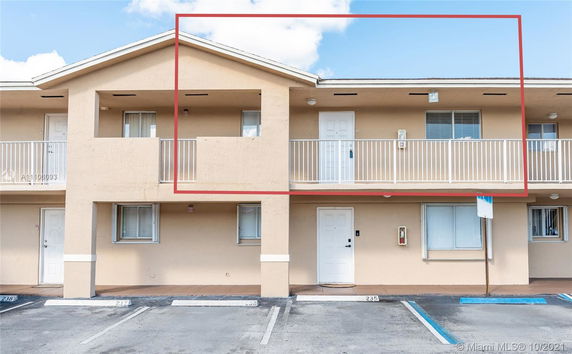 Front view of a two-story building with balconies and parking spaces.