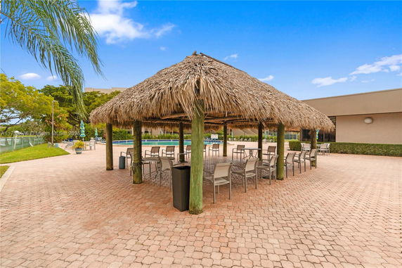 Outdoor seating area with a thatched roof structure and tables.
