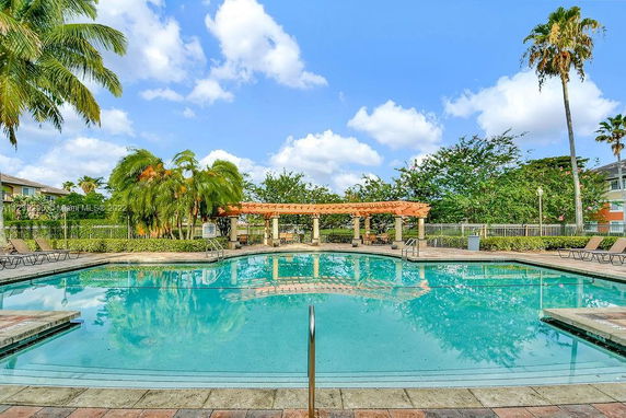 Outdoor swimming pool surrounded by lounge chairs and palm trees.