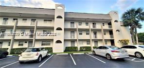 Front view of a multi-story residential building with balconies and parking spaces.