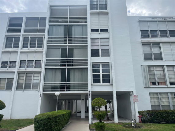 Front view of a multi-story building with large windows and white exterior.