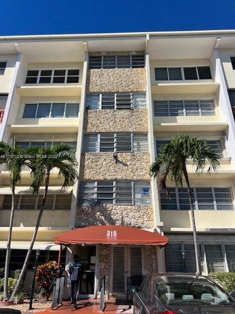Front view of a multi-story building with stone facade and red awning.