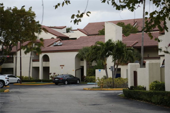 Front view of a multi-story building with tile roofing and arched entryways.