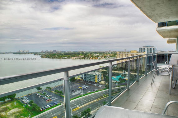 View from a high-rise building balcony overlooking a river and cityscape with surrounding buildings.