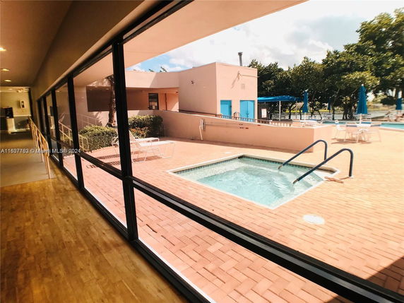 Outdoor area with a small pool and lounging chairs, surrounded by a brick patio.