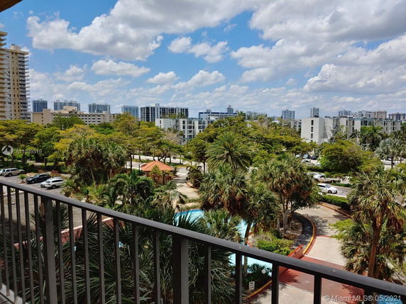 Panoramic view of a cityscape with multiple residential buildings and green spaces from a balcony.