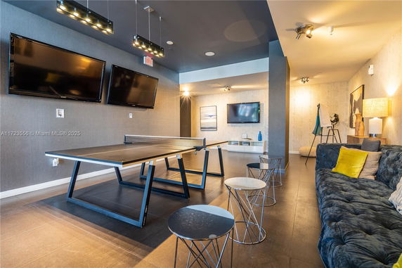 Indoor recreational area with a ping pong table and seating arrangements.