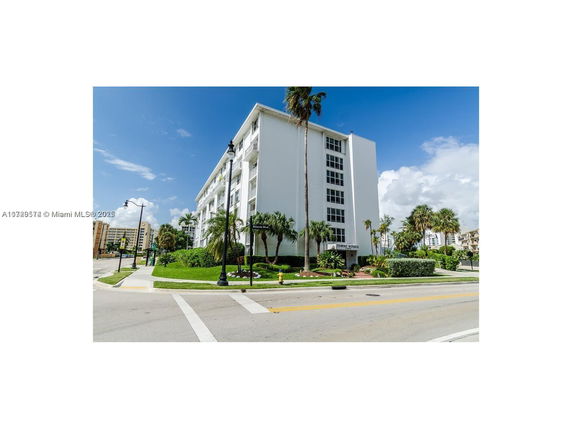 Front view of a multi-story residential building with a surrounding garden.