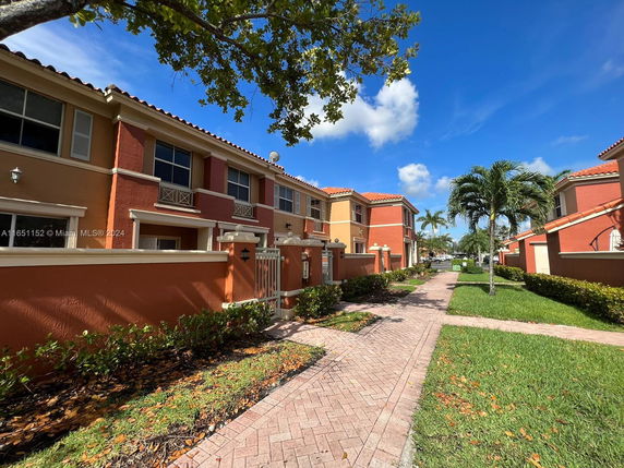 Front view of a two-story building with a gated entrance and red-orange exterior walls.