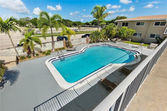 Outdoor swimming pool area with surrounding palm trees and sun loungers.
