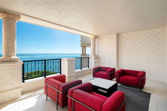 Covered terrace with red armchairs overlooking the ocean.