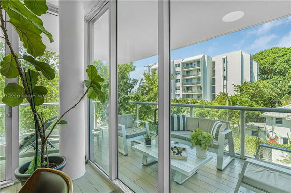 Balcony view from an apartment overlooking nearby residential buildings and lush greenery.
