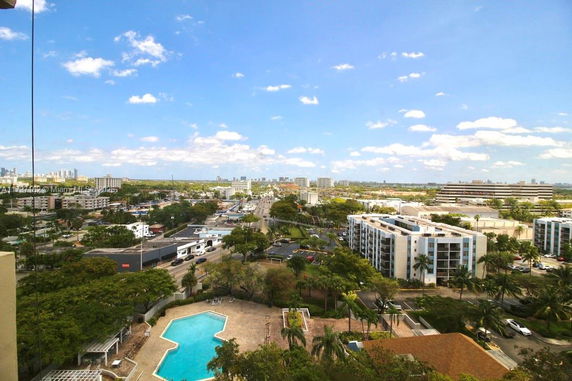 Aerial view of an urban area with a swimming pool, various buildings, and cityscape in the background.