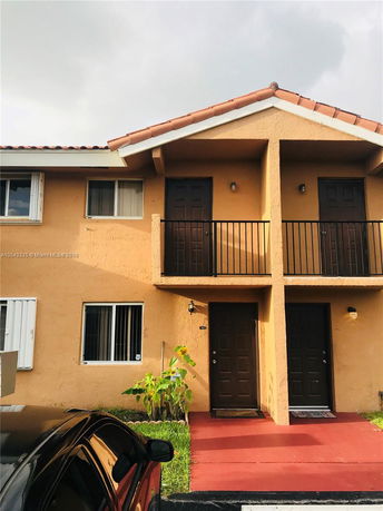 Front view of a two-story house with balconies and brown doors.