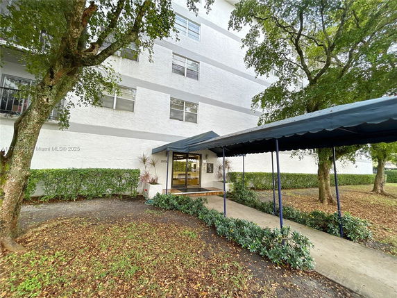 Front view of a multi-story building with a covered walkway entrance.