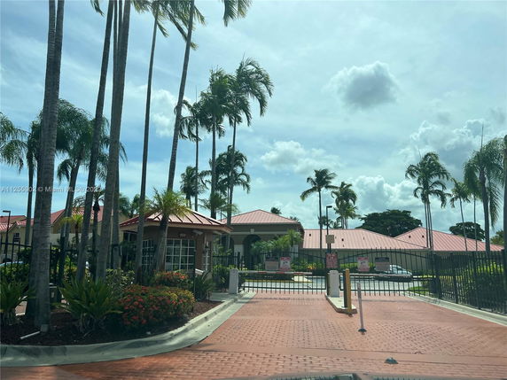 Front view of a residential area with red-roofed buildings and gated entrance.