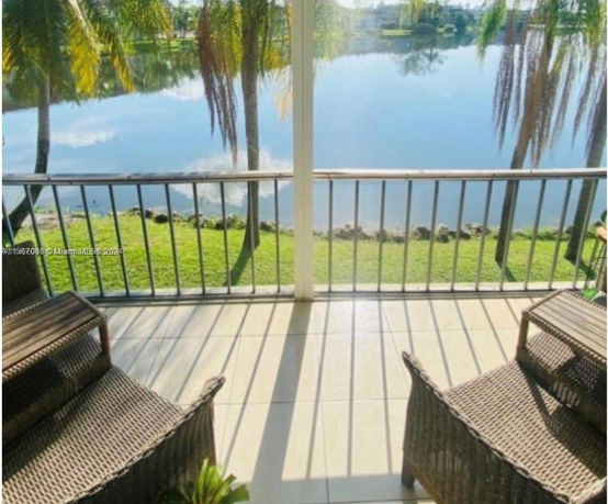Balcony view overlooking a calm lake and greenery.