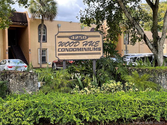 Front view of a condominium complex with a sign reading 'Wood Hive Condominiums'.