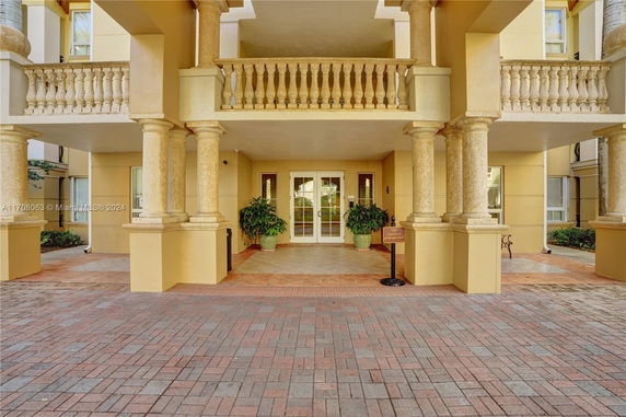 Front view of a building entrance with columns and decorative balcony.