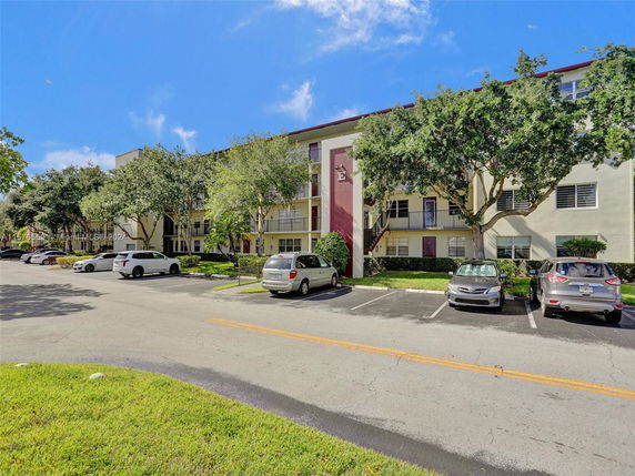 Front view of a multi-story residential building with parking area.